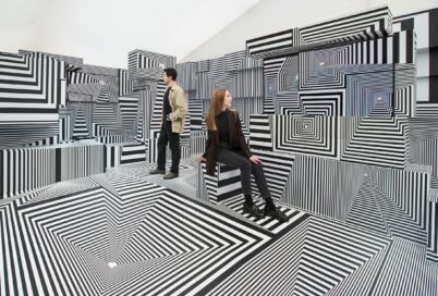 Two visitors posing at LG OLED-powered “Into the Maze” installation by the German artist, Tobias Rehberger