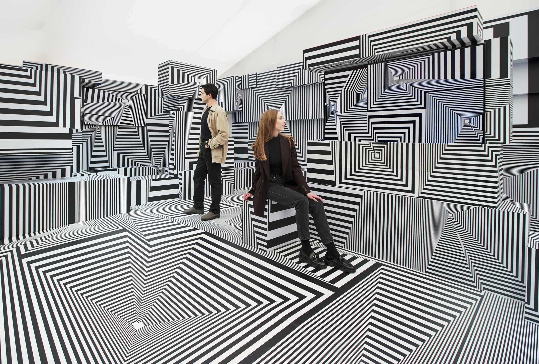 Two visitors posing at LG OLED-powered “Into the Maze” installation by the German artist, Tobias Rehberger