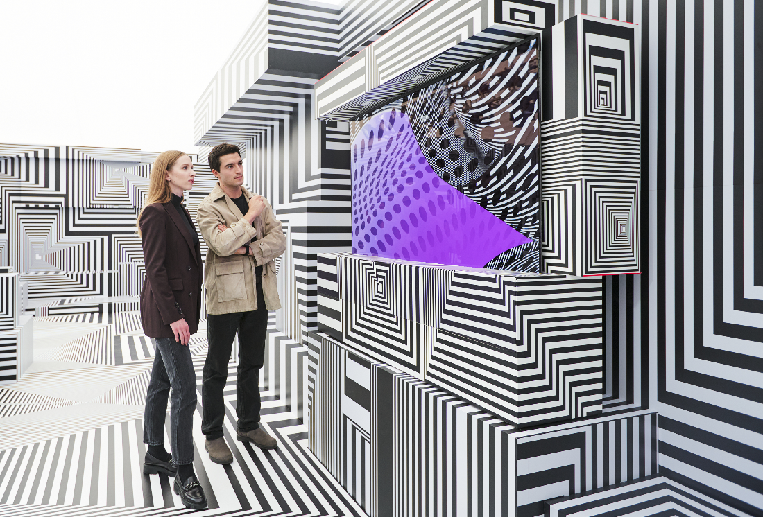 Two visitors taking a closer look at LG OLED-powered “Into the Maze” installation by the German artist, Tobias Rehberger