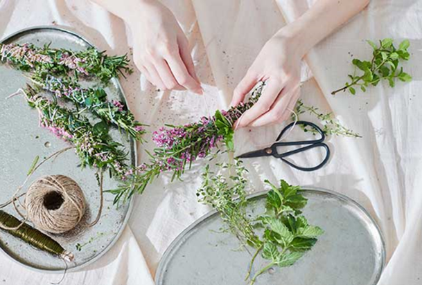 A person is making some decorations using flowers and plants