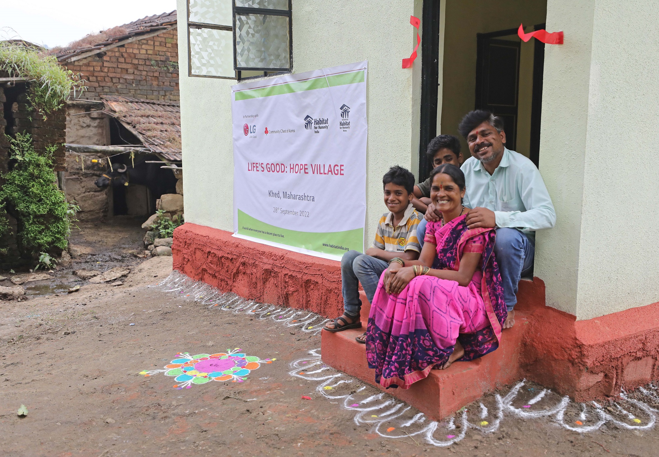 An Indian family posing together at the entrance of their house that was rebuilt through Life's Good: Hope Village project