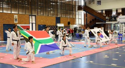 Taekwondo athletes holding the national flags of South Africa and Korea at the end of their performance
