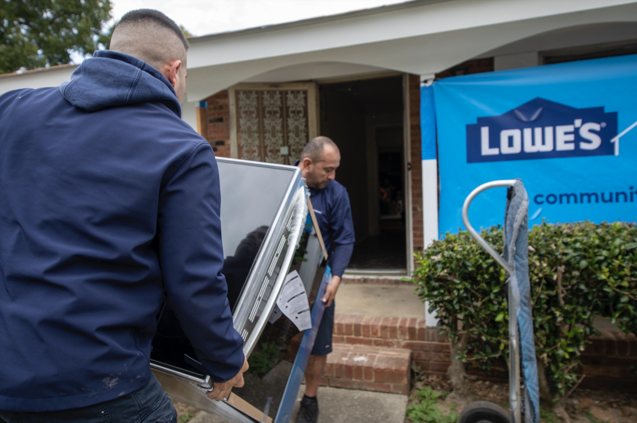 Volunteers carrying the donated LG appliance inside house