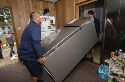 Volunteers carrying the donated LG refrigerator