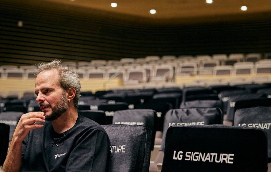 Yoann Bourgeois, the performance artist and choreographer, sitting in an empty LG SIGNATURE Hall at LG Arts Center SEOUL, as he looks onto the stage