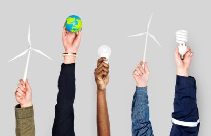 Five people holding up miniature windmills, miniature earth and lightbulbs