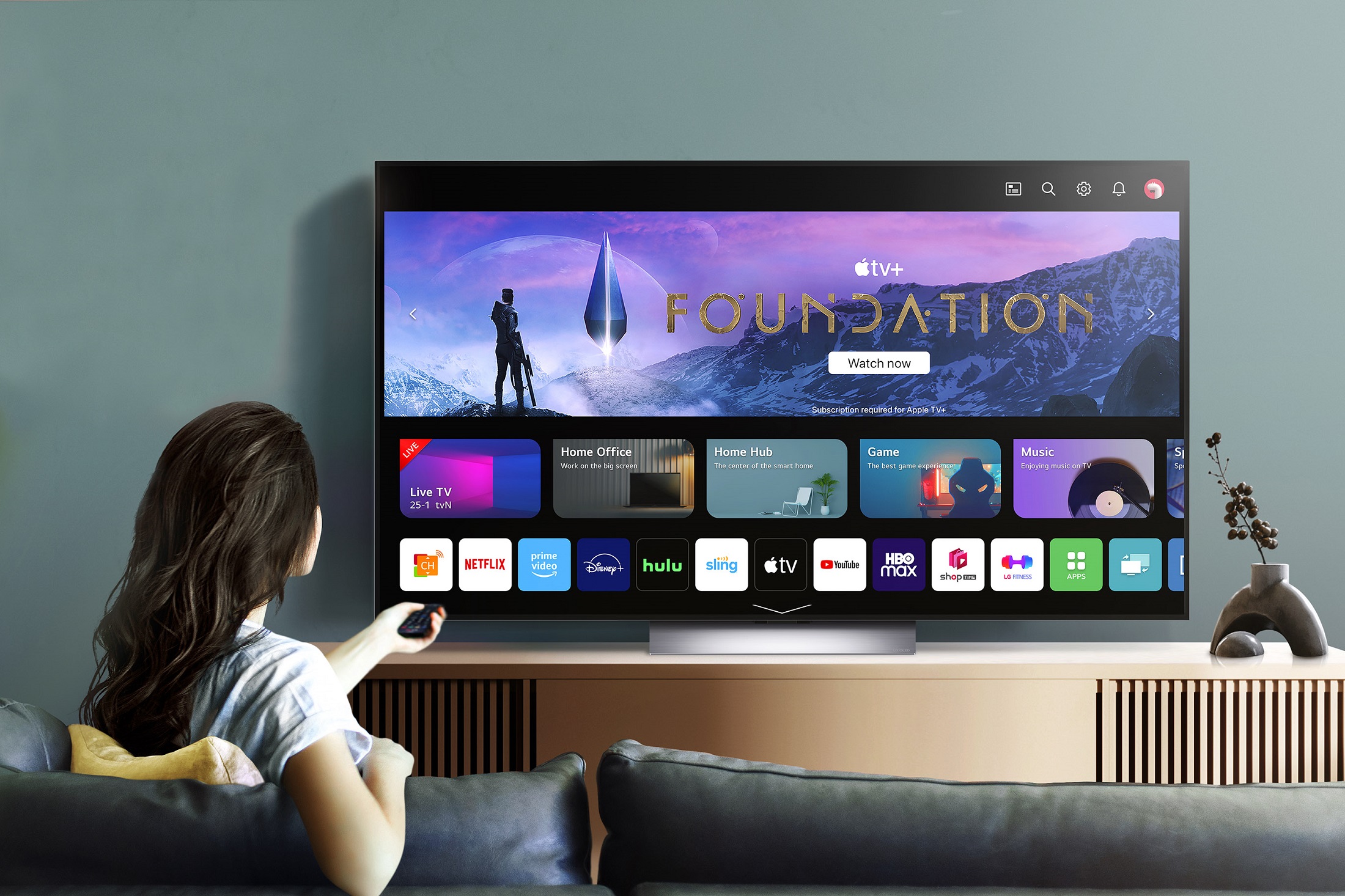 A woman scrolling through the various applications available on the 2023 LG OLED TV, including Apple TV+ which comes free