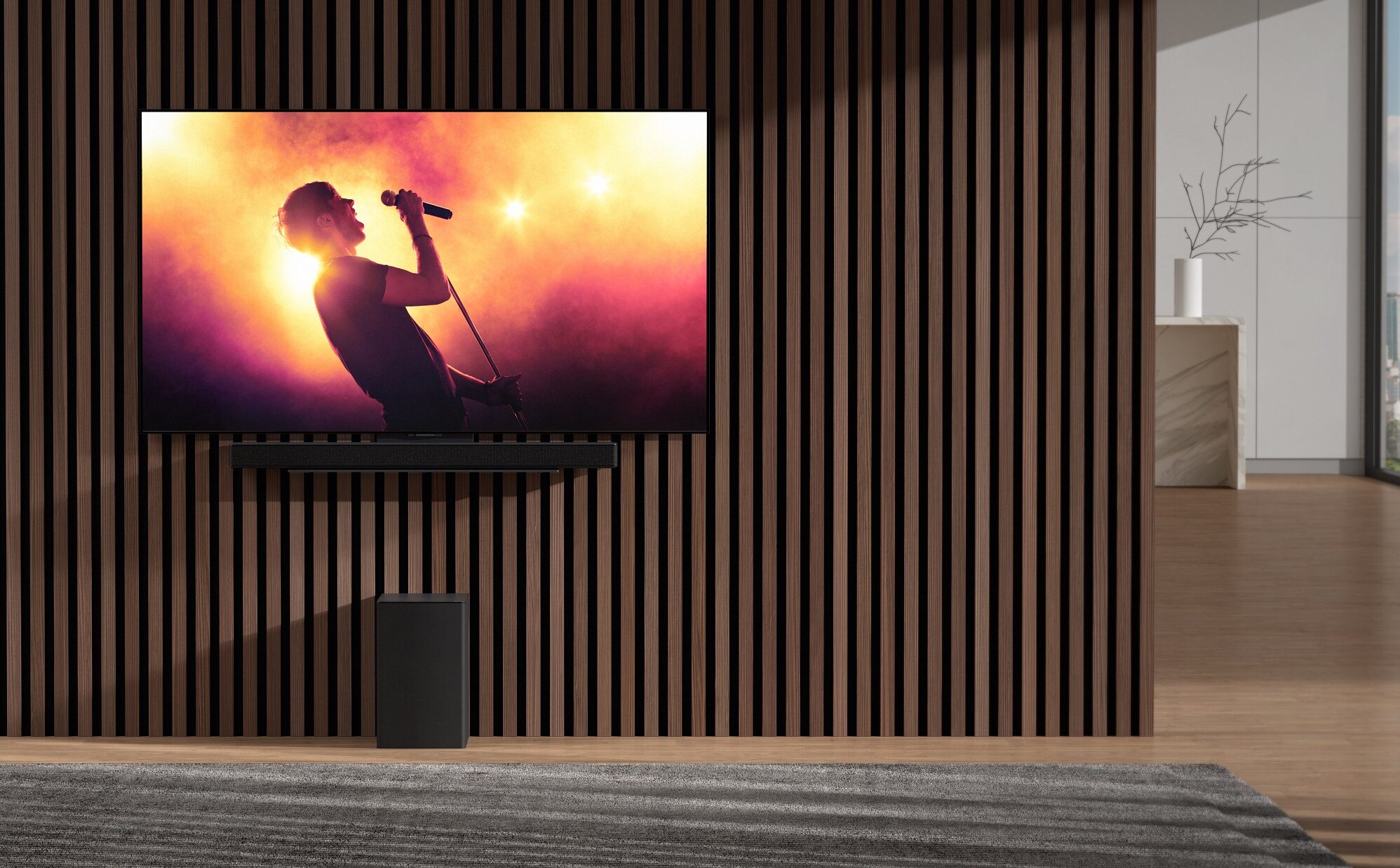 Nnew LG sSoundbar and wireless subwoofer harmonizing with an LG TV in an apartment as it displays a music concert with bright lights