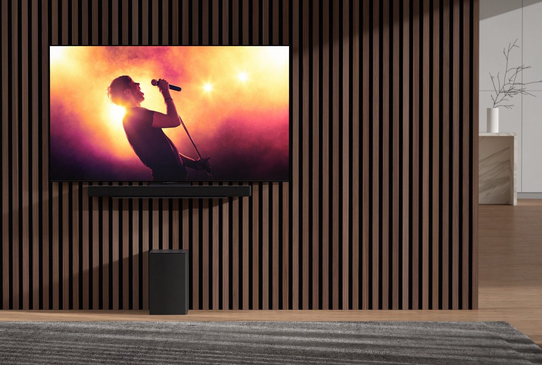 Nnew LG sSoundbar and wireless subwoofer harmonizing with an LG TV in an apartment as it displays a music concert with bright lights