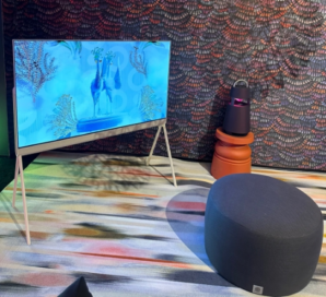 LG OLED Objet Collection Pose standing in the corner of a colorful room at CES 2023 next to the LG XBOOM speaker in black