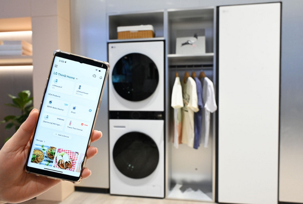 LG WashTower™ laundry solution and Styler are displayed at CES 2023 exhibition with a smartphone on the left displays LG ThinQ app