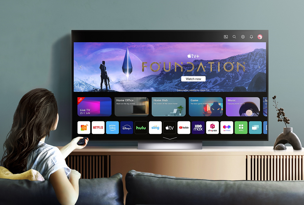 A woman scrolling through the various applications available on the 2023 LG OLED TV, including Apple TV+ which comes free
