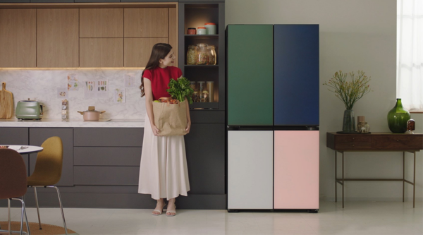 A woman holding a bag of groceries is standing next to LG MoodUP InstaView™ refrigerator
