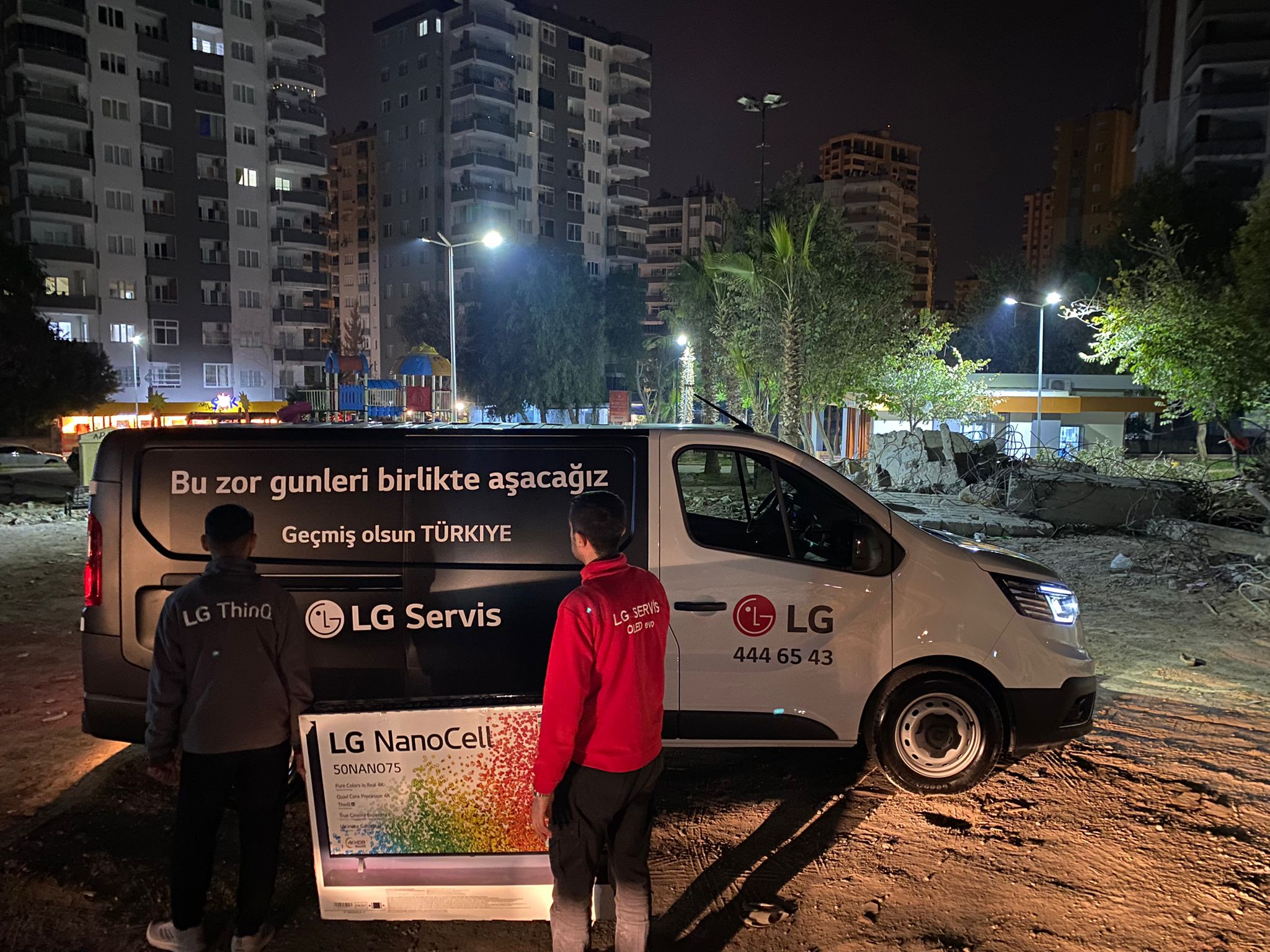 Photo of LG employees carrying LG NanoCell TV in front of LG vehicle