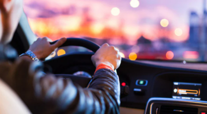 A person driving a car at sunset