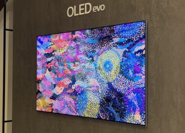 A wall-mounted 2023 LG OLED evo TV displaying brilliant colorful artwork resembling flowers at the 2023 showcase.