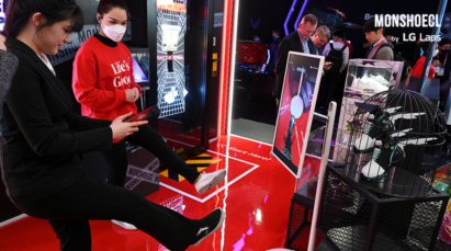 A corner of LG's booth decorated with Monshoecl products during CES 2023 where a visitor is trying on the shoe virtually with her smartphone