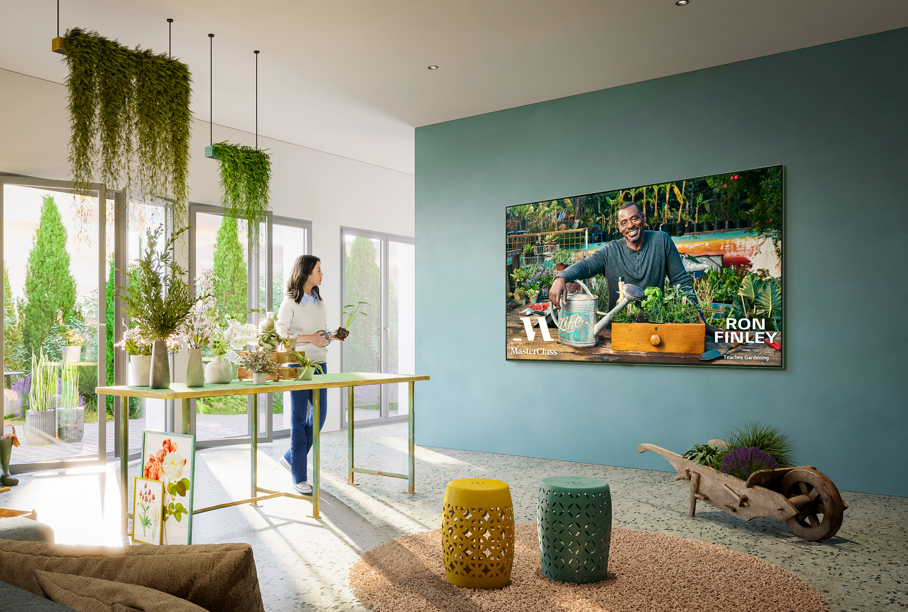 A woman watching a gardening lesson from the MasterClass app on her wall-mounted LG Smart TV as she tends to her plants