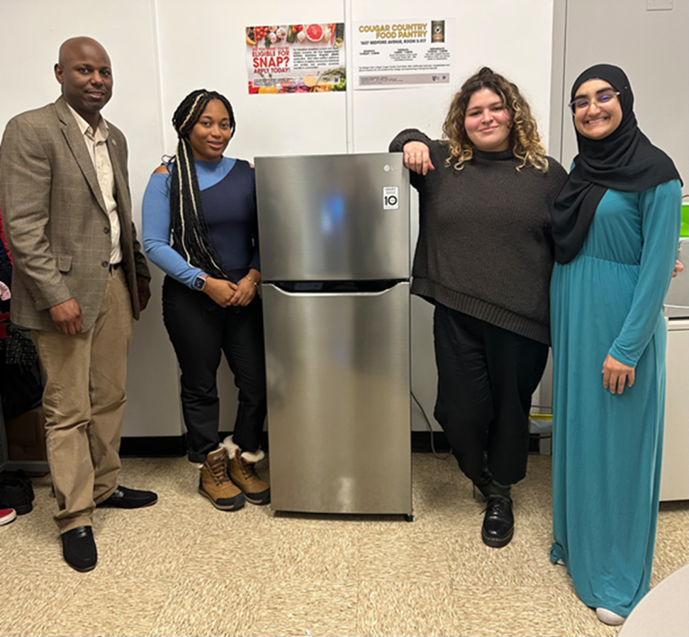 Four people posing with a refrigerator donated by LG