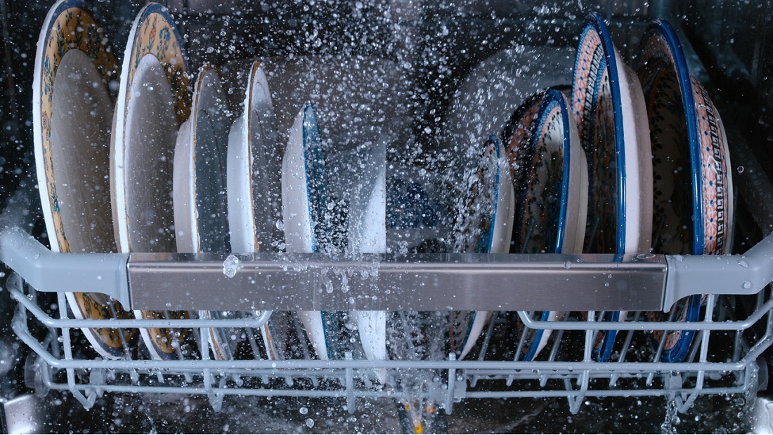 A bunch of dishes put neatly in a dishwasher and being washed