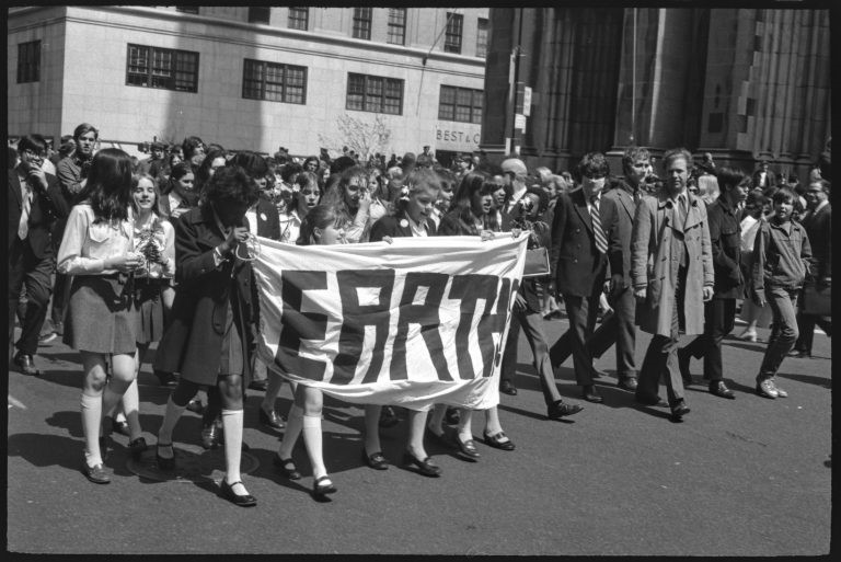 A old photo of people marching with a placard that reads 