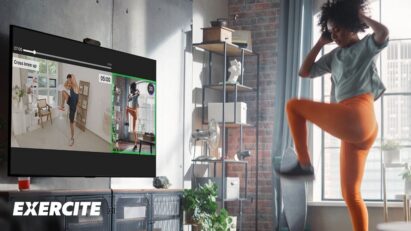 A woman uses a camera to improve her form as she exercises along to a Xponential+ video in her living room