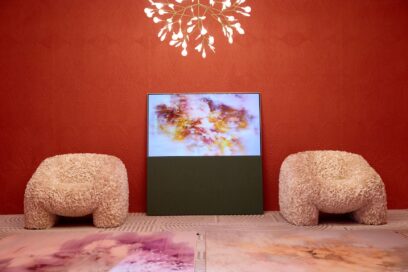 LG OLED Objet Collection Posé positioned between two sofas as it displays artwork in a red-themed showroom