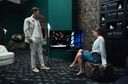 A man and woman admire the LG OLED Objet Collection Posé model in the center of a green-themed space designed by Dutch brand Moooi