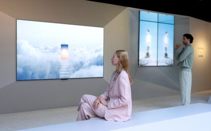 A man and woman admiring an artwork of bright clouds through an LG OLED TV at the LG OLED Art exhibition