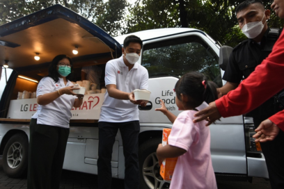 LG Indonesia staff handing over prepared food to a young girl during LG Lebaran Sehat event