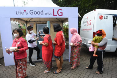 LG Indonesia staff handing over a bottle of water to people waiting in line during the annual LG Lebaran Sehat event