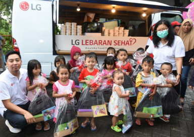 LG Indonesia staff posing together with children all holding a bag of goods provided by LG during LG Lebaran Sehat event