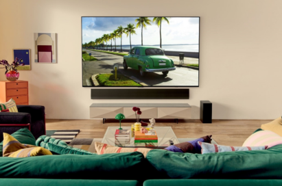 LG OLED TV in a bright living room displaying a green car driving down a road by the beach