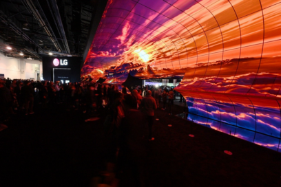 A crowd enter the LG OLED TV showroom at CES through an expansive installation of LG displays depicting a beautiful sunrise