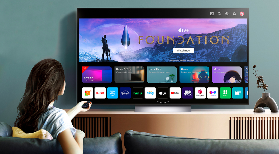 A woman scrolling through various applications available on the 2023 LG OLED TV, including Apple TV+’s show, Foundation