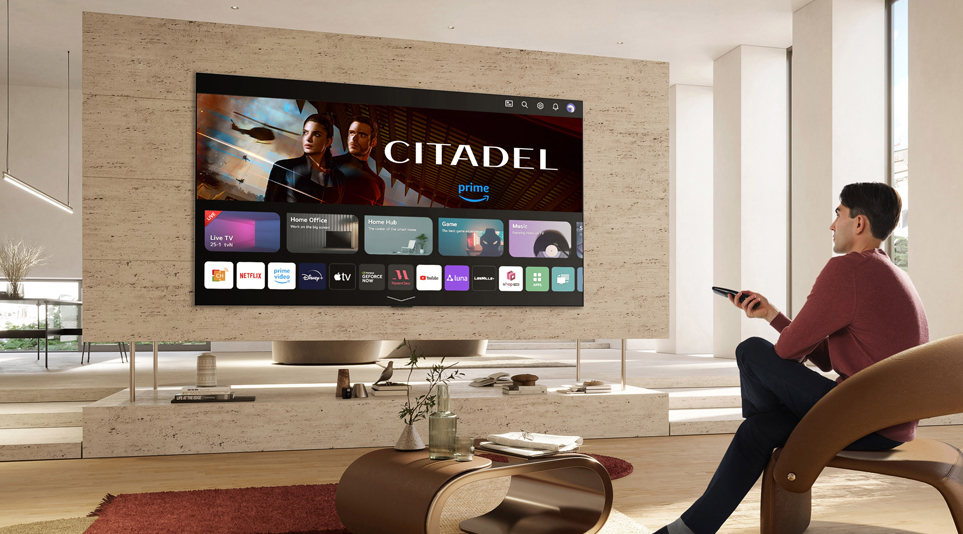 A man sitting in a stylish, bright living room as he navigates the webOS 23 platform which is now promoting CITADEL on Prime