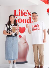 LG CEO posing with LG employee in front of the white wall decorated with a phrase 
