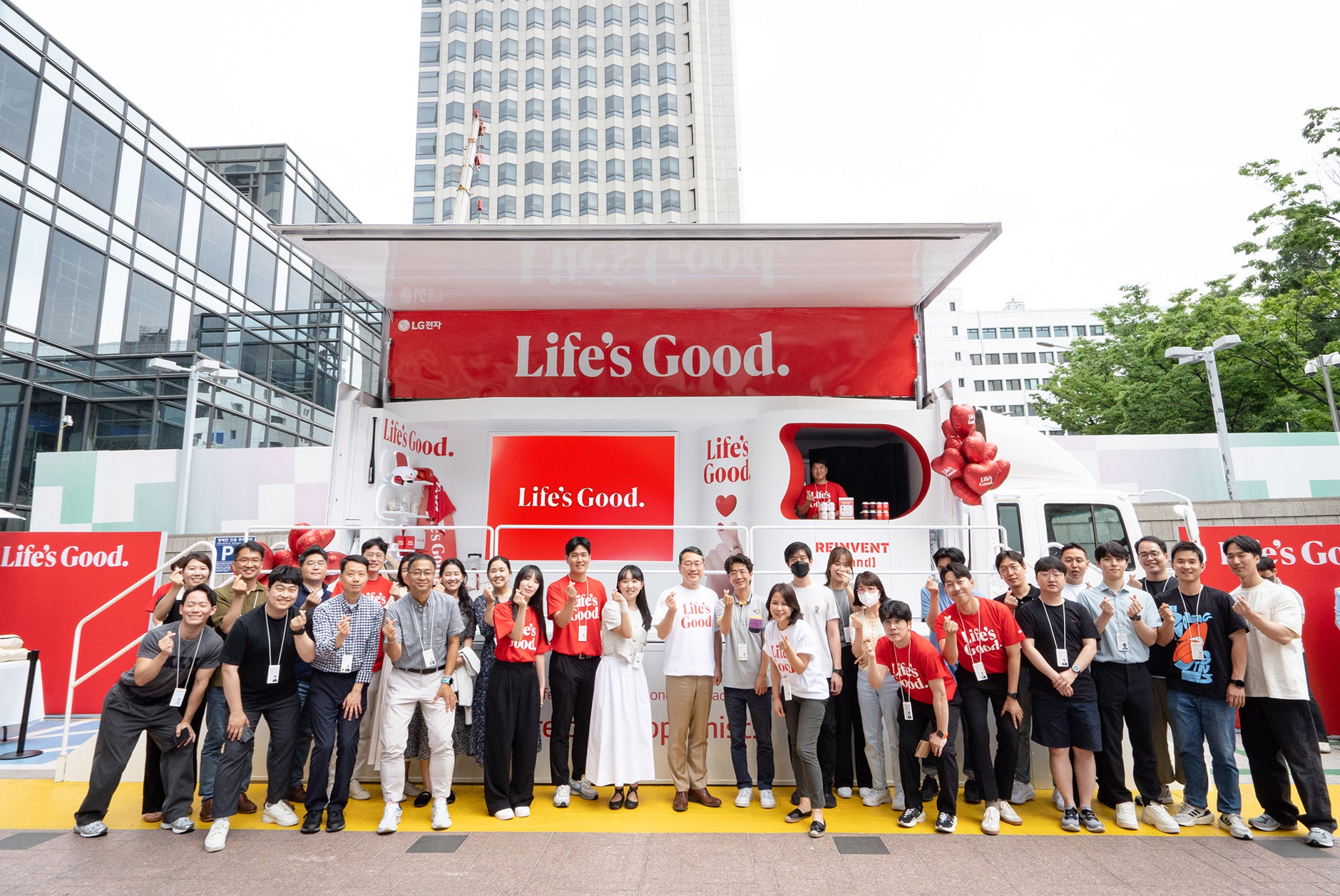 LG CEO and employees posing together for a photo in front to the Life's Good event truck 