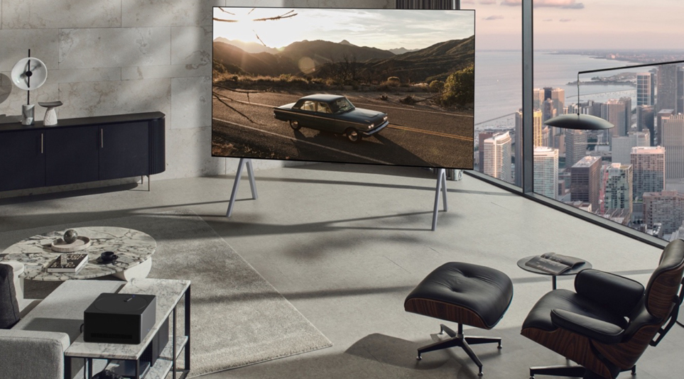 LG OLED M3 displaying a car riding on a country road inside a modern living room of a high-rise apartment