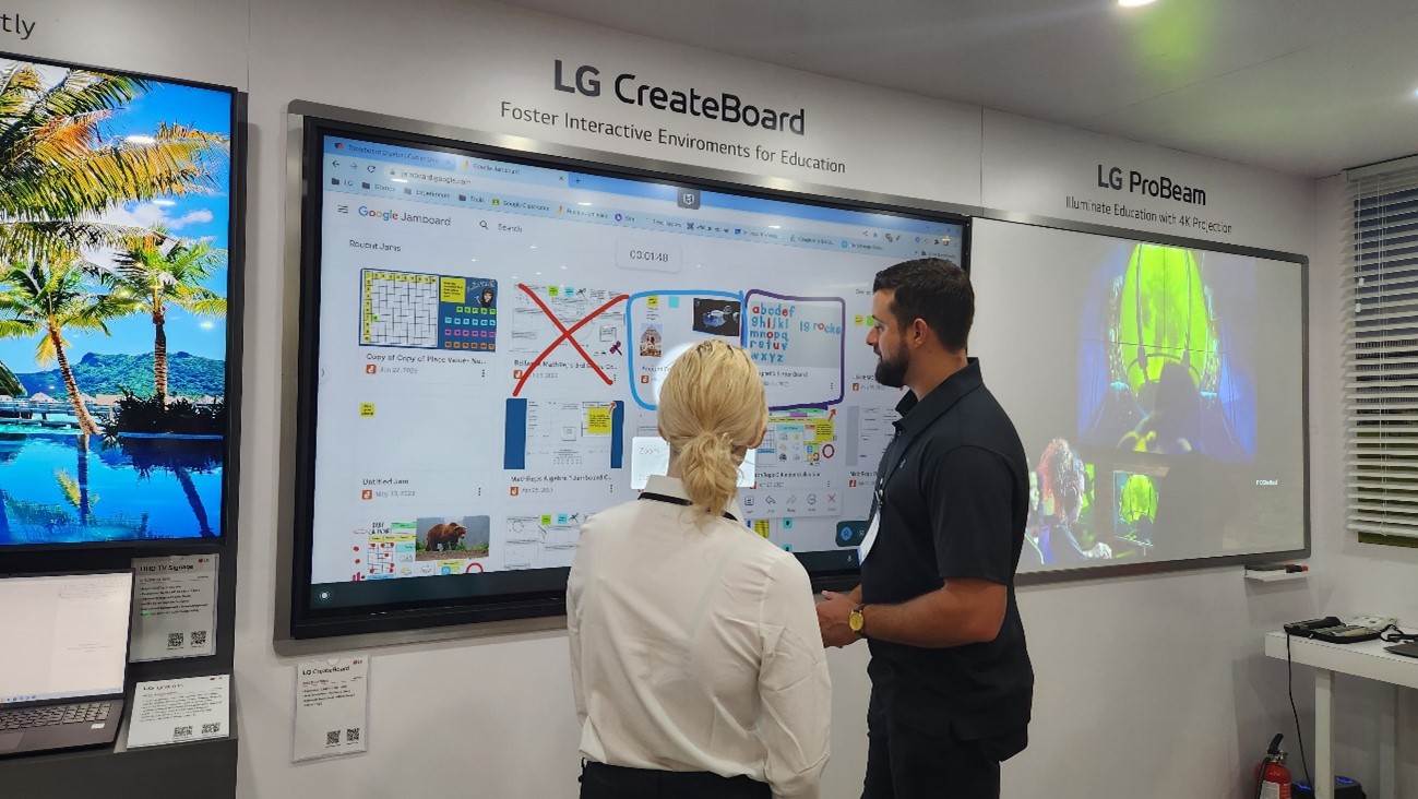 Two people talking in front of LG CreateBoard