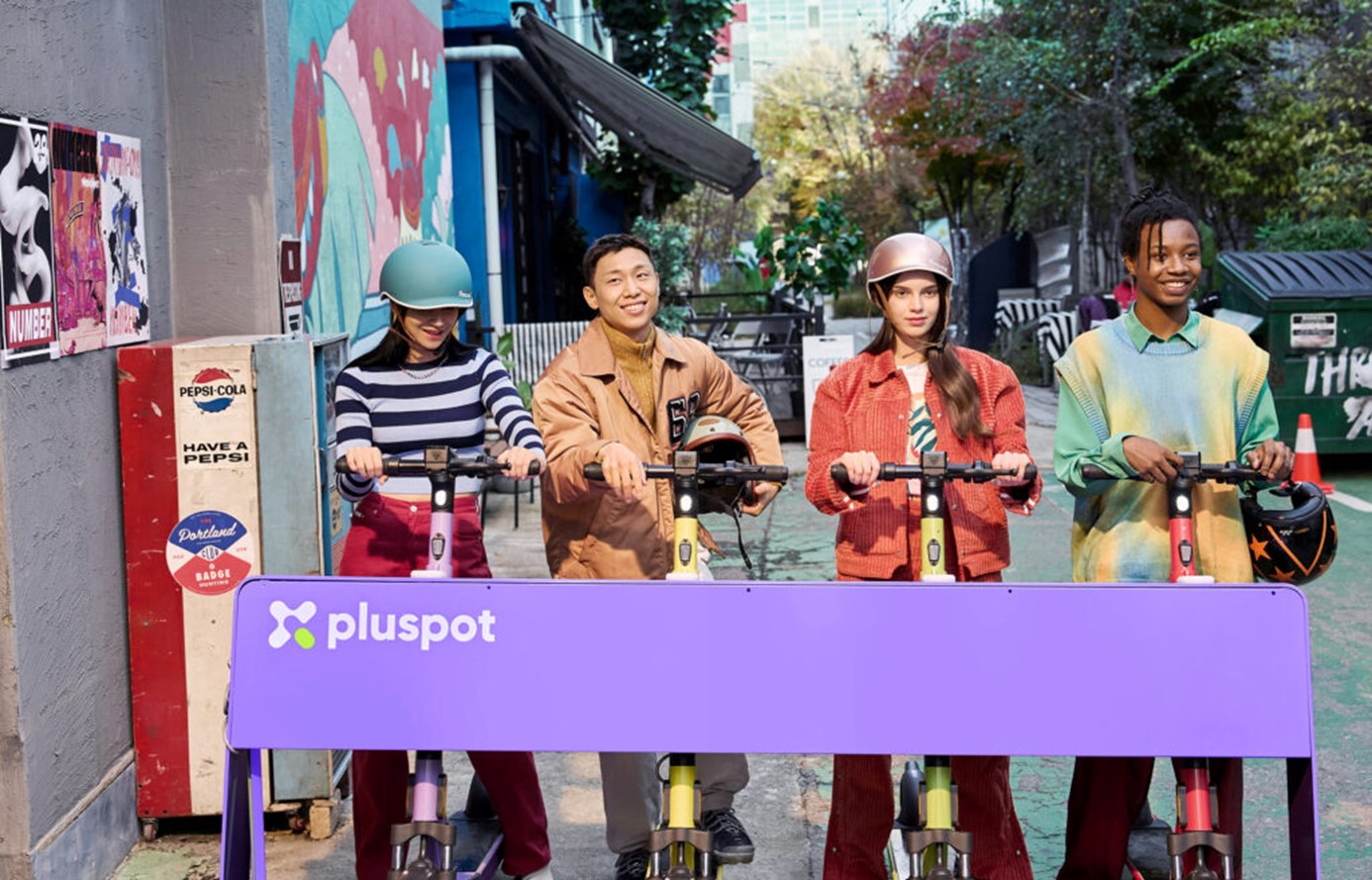 Four people using pluspot's scooters parked at the charging station