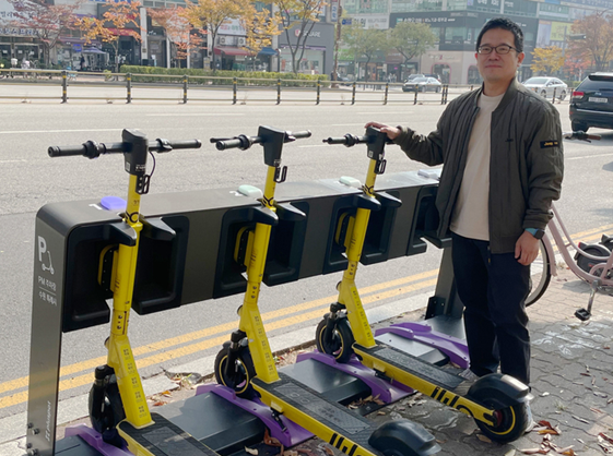 Do Won-dong, CIC head of LG’s CurrentDot company, posing with pluspot's scooters being charged at the station