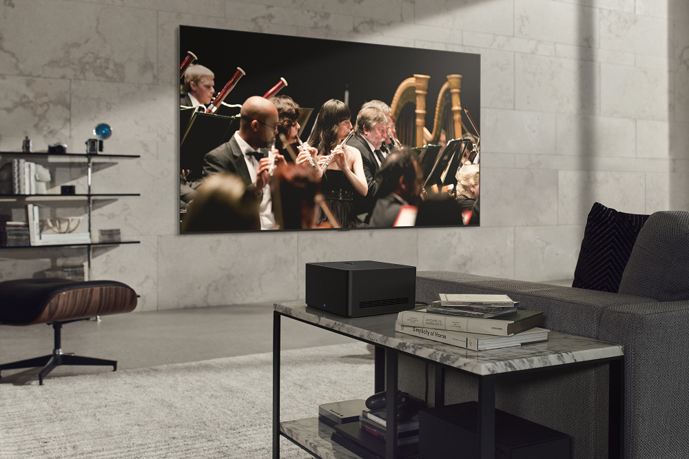 The newly revealed LG SIGNATURE OLED M3 TV mounted on the wall of a gray-themed living room as it displays an orchestra performance