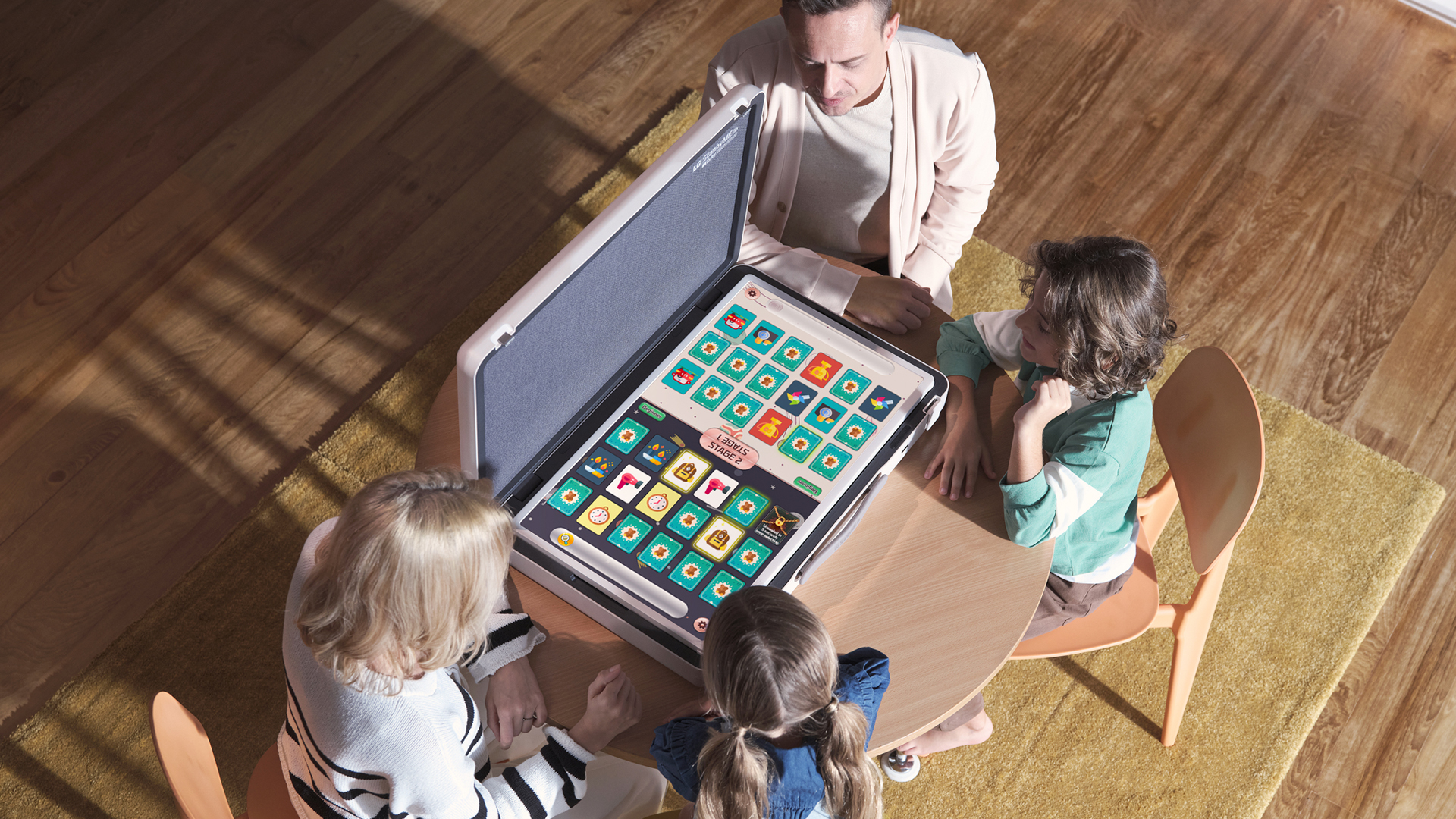 A family of four playing a board game on the LG StanbyME Go’s fat display