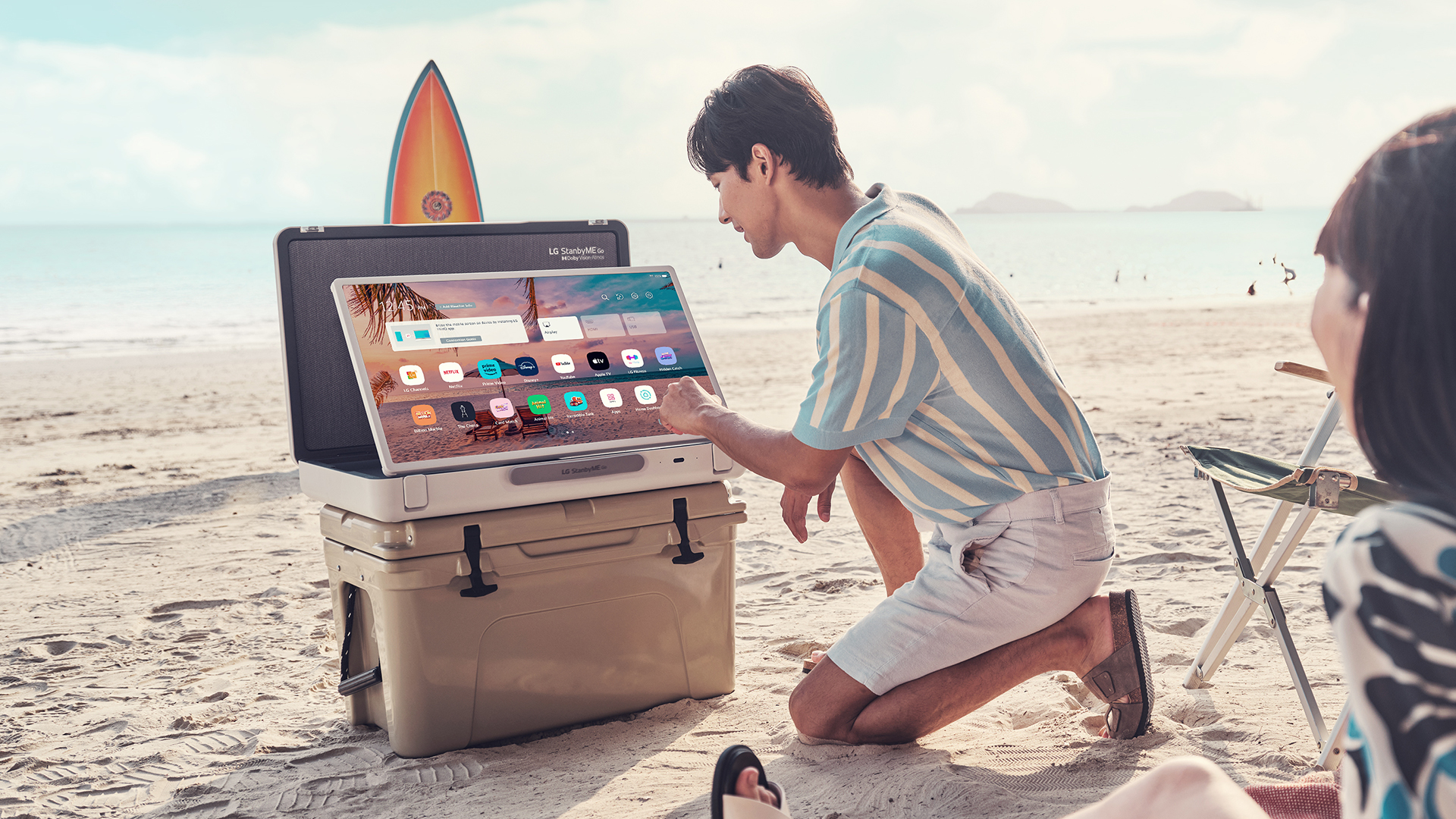 A couple using LG StanbyME Go on a sandy beach