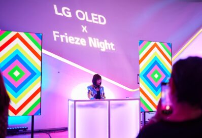 A woman in a colorful outfit DJing at LG OLED X Frieze Night