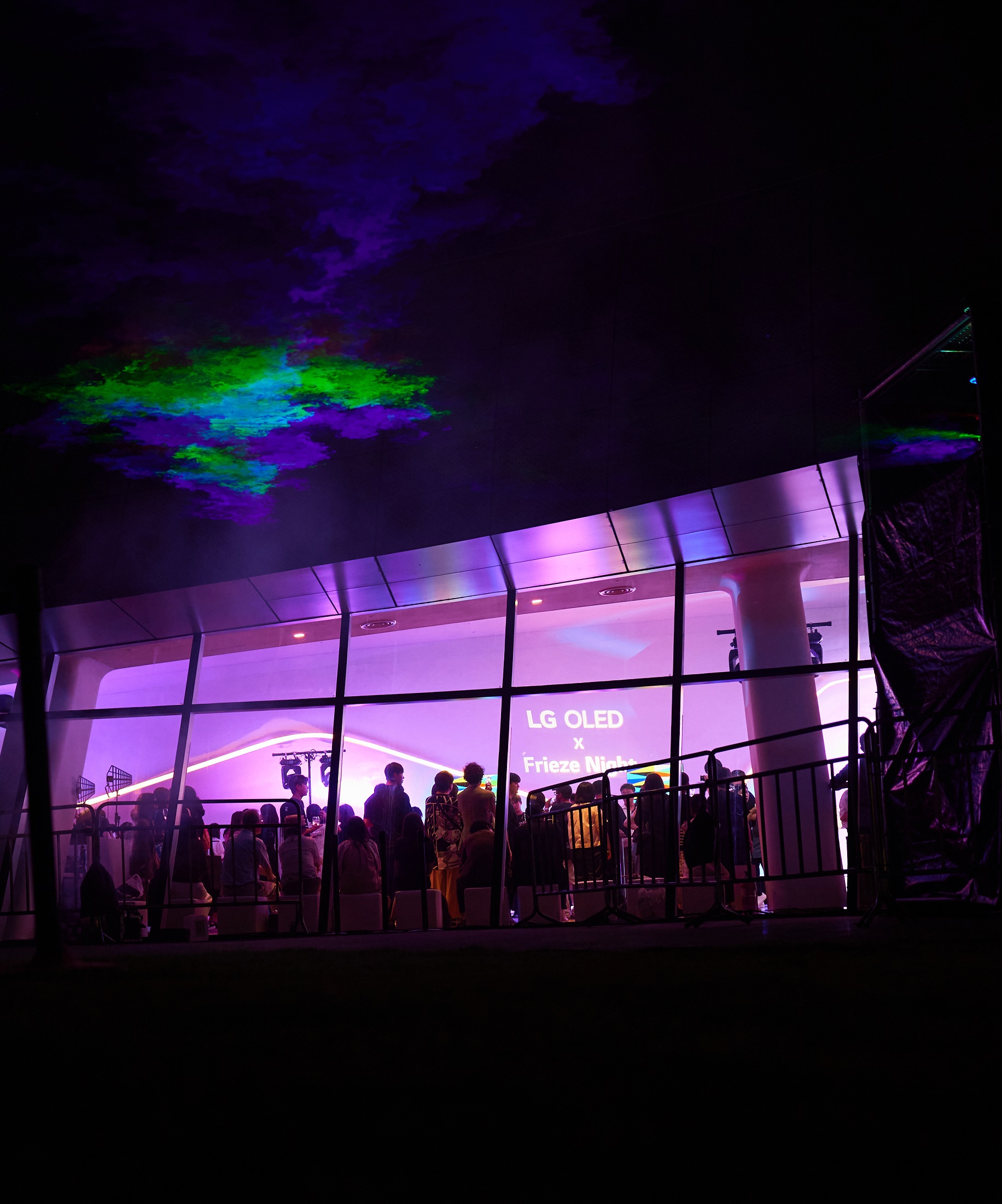 LG OLED X Frieze Night attendees reflected in the glass on the wall of Dongdaemun Design Plaza