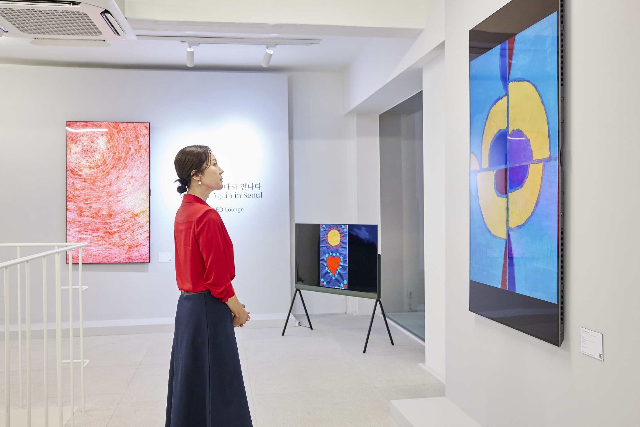 A woman in a red shirt admires the artwork on display at Frieze Seoul 2023