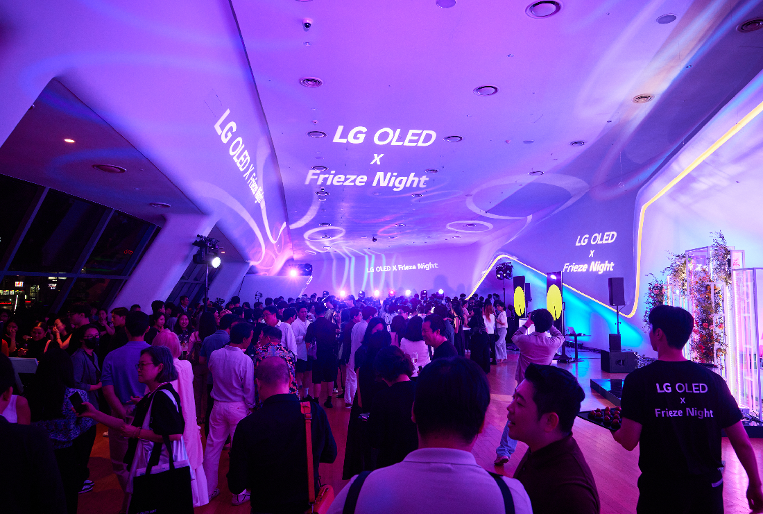 LG OLED X Frieze Night attendees reflected in the glass on the wall of Dongdaemun Design Plaza