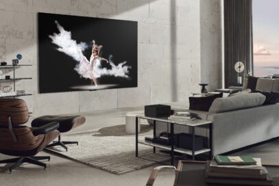 A wall-mounted LG SIGNATURE OLED M3 model displays an image of a woman performing ballet in a modern, gray-toned living room